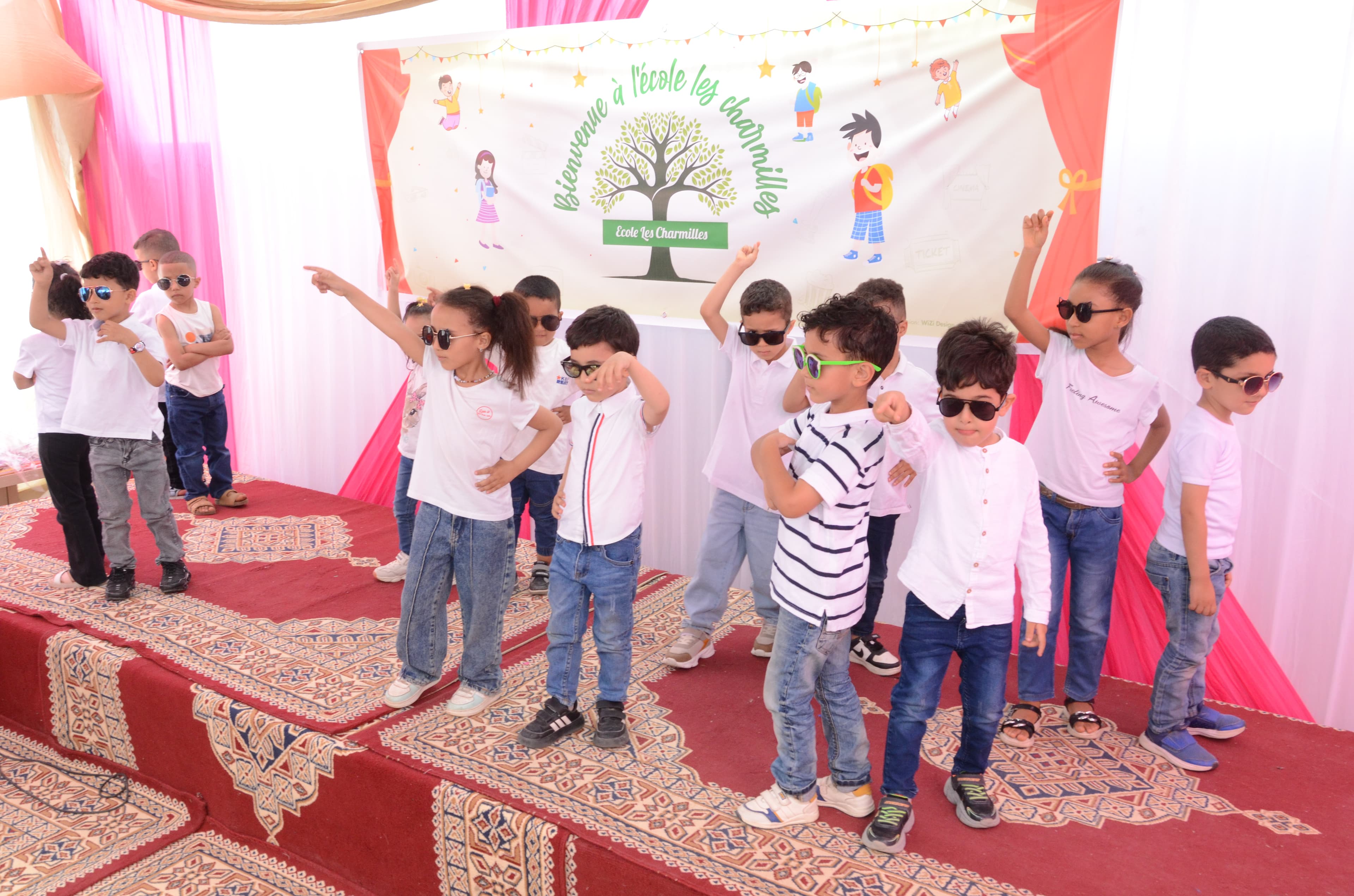 Garçons et filles portant des lunettes de soleil et des vêtements décontractés en train de danser avec énergie sur scène.